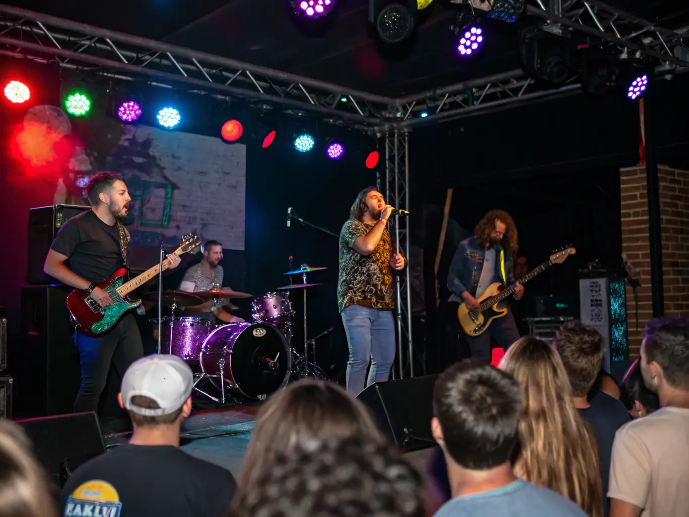 A photograph capturing a lively cultural event at Coton Tige, featuring musicians performing on stage, attendees enjoying the music, and colorful decorations enhancing the festive atmosphere.